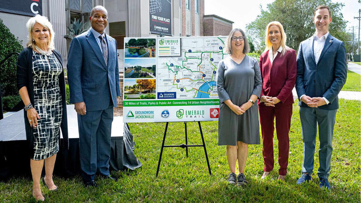 Project stakeholders standing with Mayor Donna Deegan next to a project map for the Emerald Trail